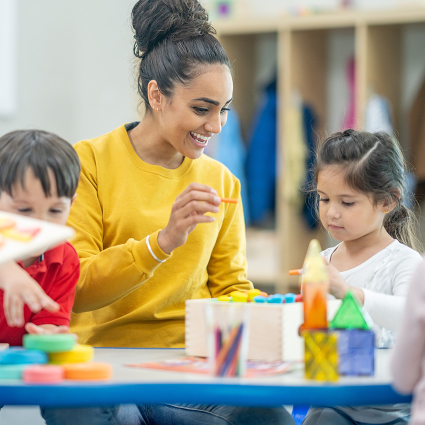 A photo of a teacher and young students painting