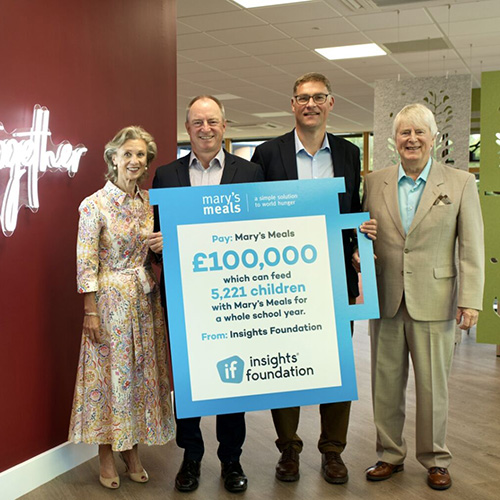 A photo of Insights leadership and others holding a sign showing Insights has donated £100,000 to Mary's meals